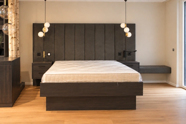 Schlafzimmer mit dunklem Bett und breitem Kopfteil